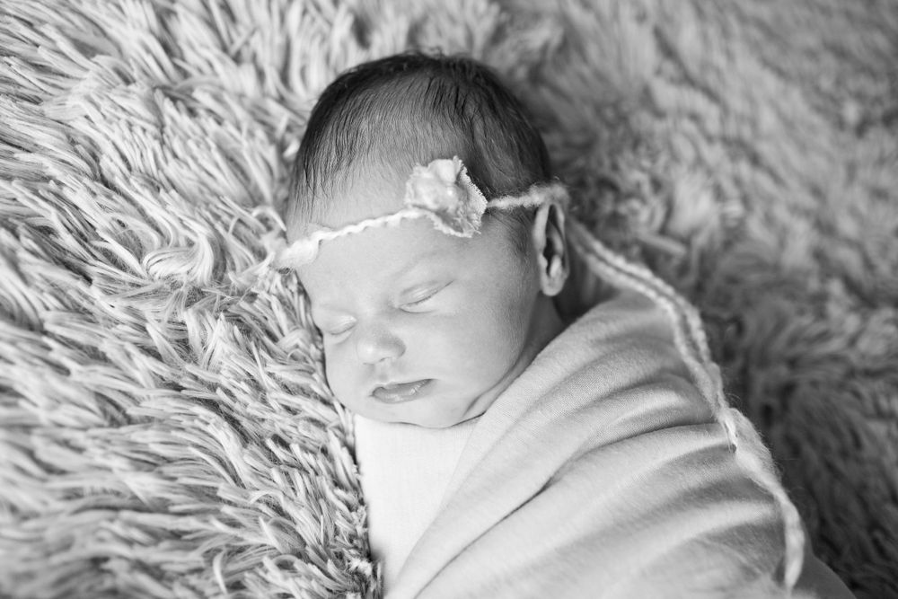 Peaceful sleeping newborn baby wrapped in soft white blanket.