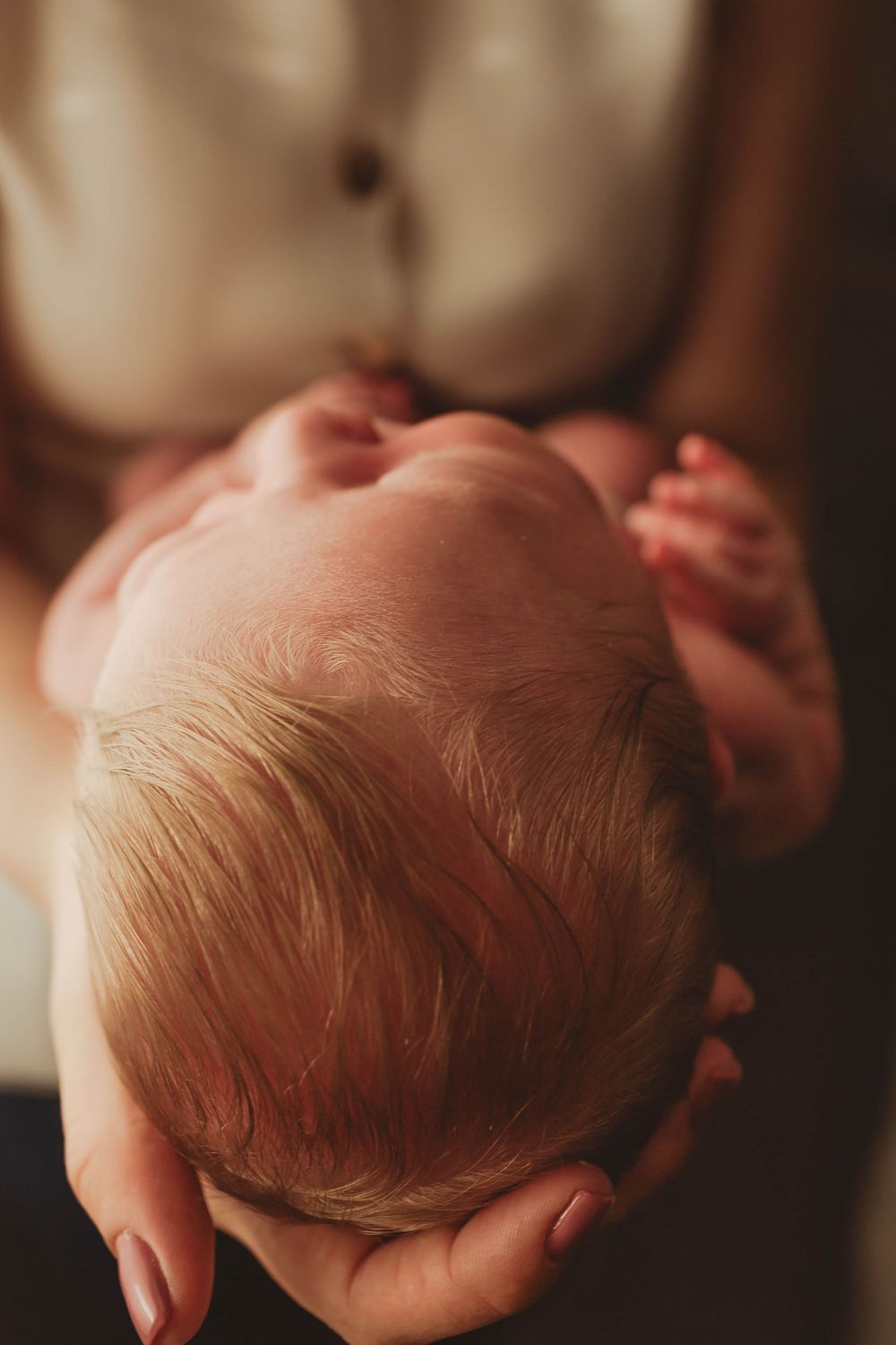 Close-up overhead view of sleeping newborn with soft natural lighting.