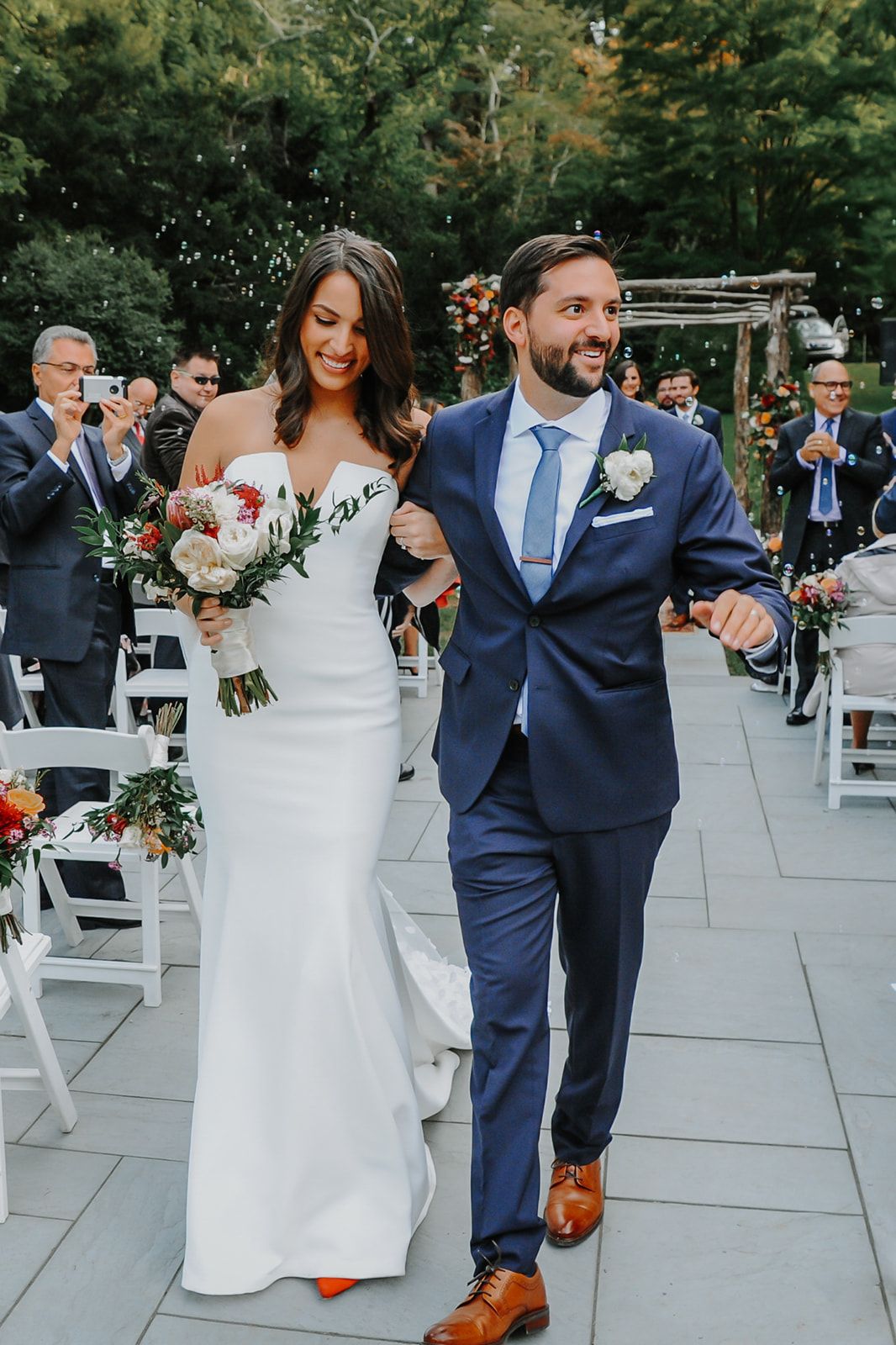 Newlyweds celebrate during outdoor wedding on stone patio at the Bailey arboretum in Long Island, NY by S. Teresa Photography Siobhan Mullan