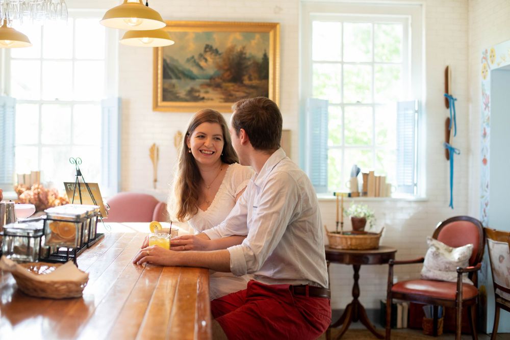 Bright interior cafe scene with couple enjoying conversation at wooden table.