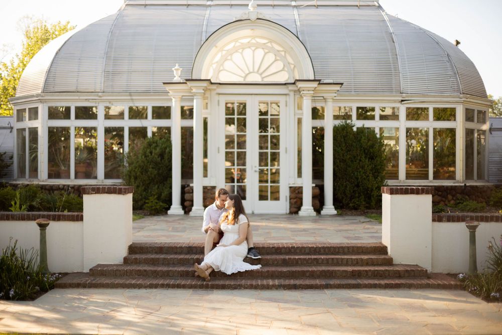 Elegant white conservatory building with columns and steps in natural daylight.