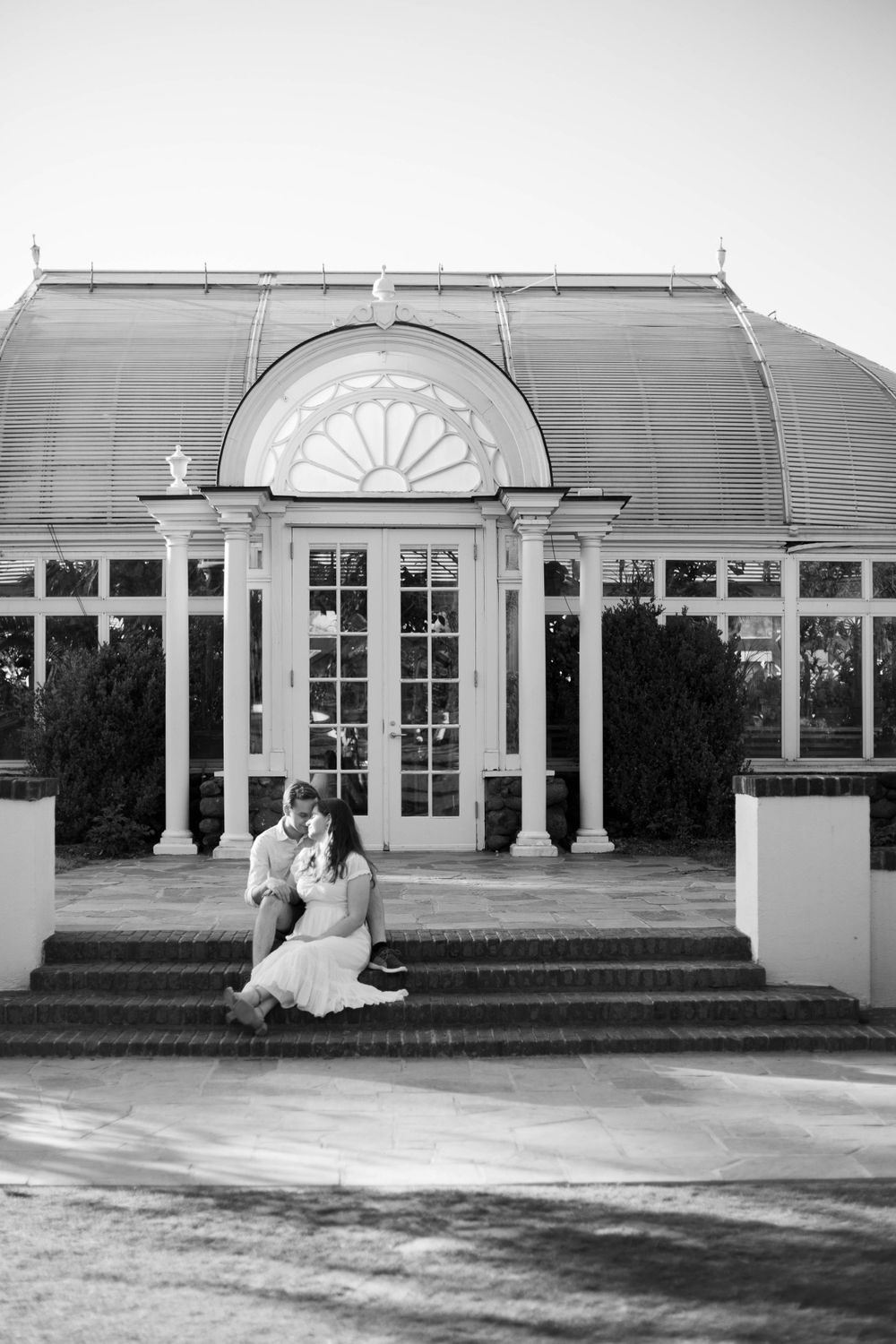 Black and white photo of a classic conservatory building with white columns and arched windows.