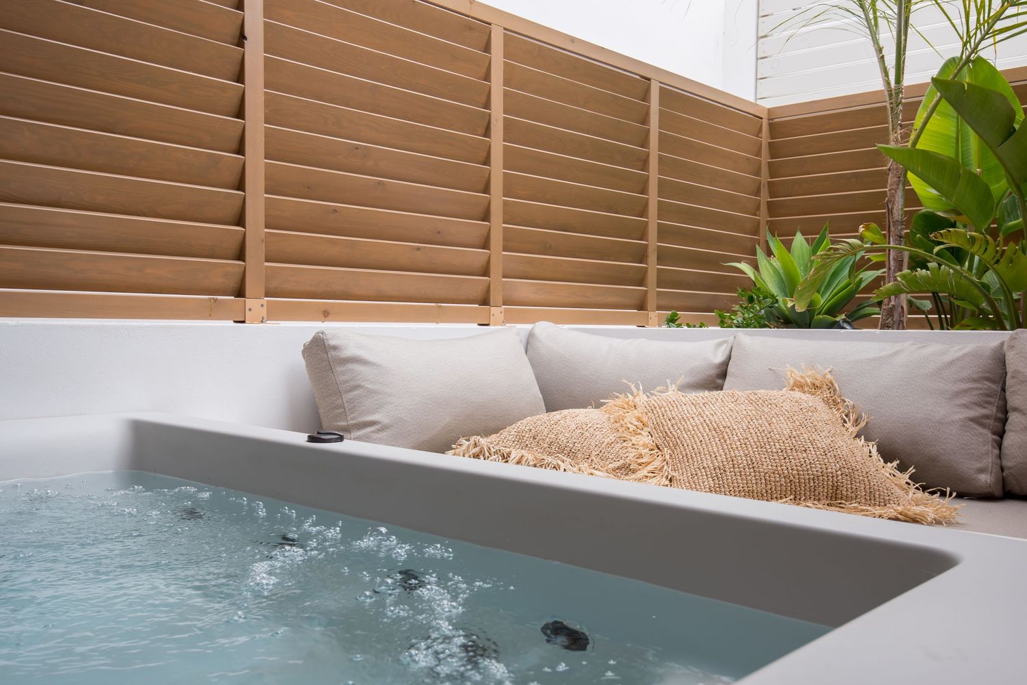 Outdoor hot tub with plush cushions and privacy fence creating an intimate relaxation space.