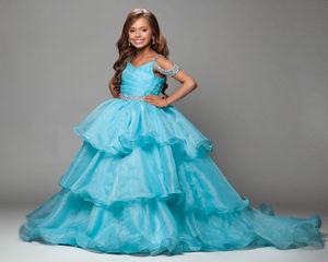 Stunning aqua blue tiered ball gown with ruffles and a sweeping train photographed against a gray backdrop.