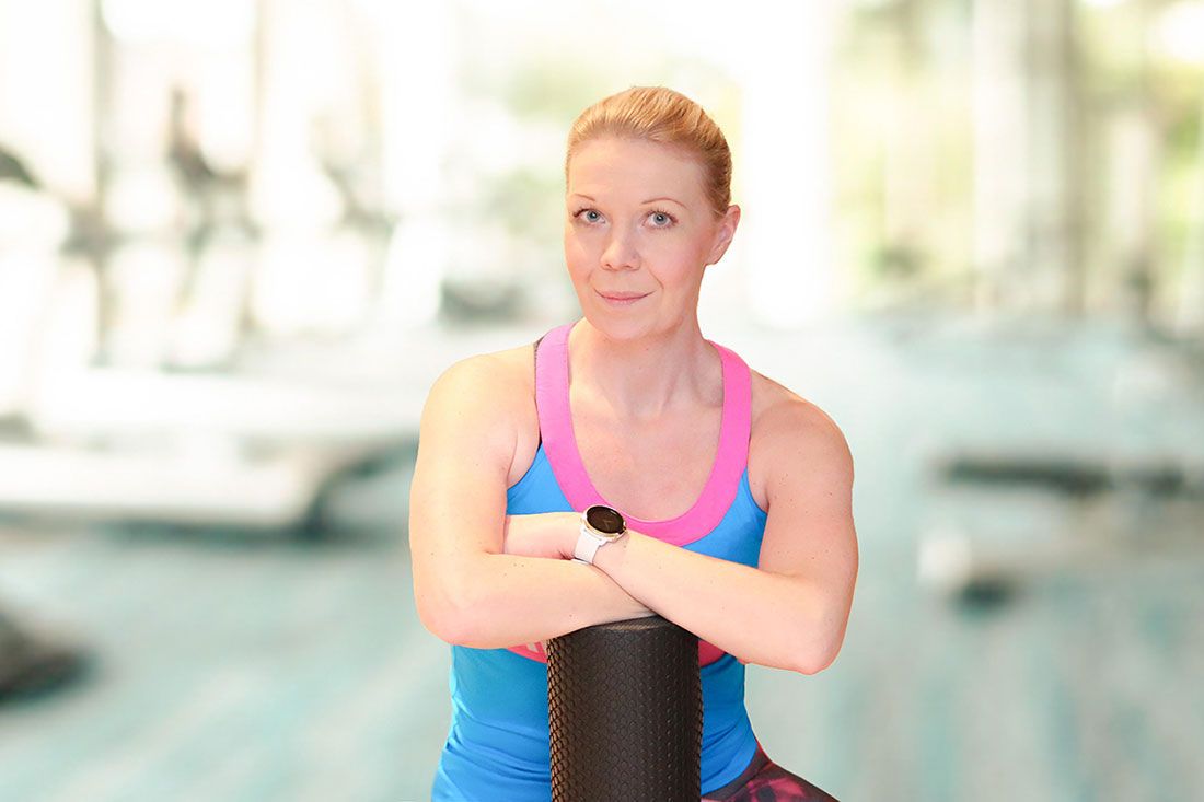 Person in blue workout attire holding foam roller at gym.