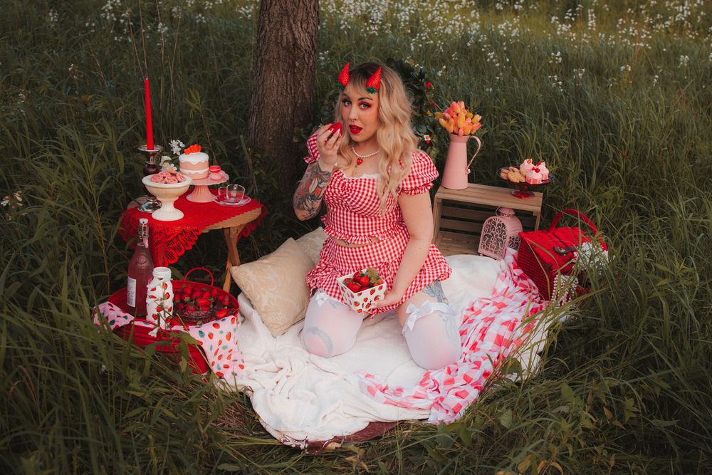 Pink and red Valentine's Day styled setting with floral arrangements and heart decorations in grass.