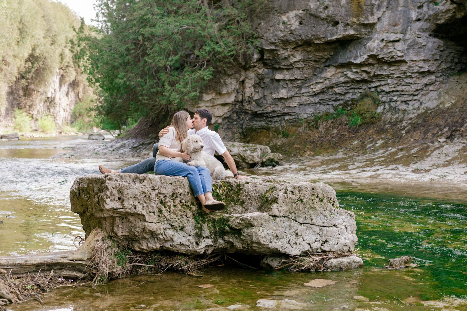 Couple sitting together on rocky outcrops near a scenic waterway.