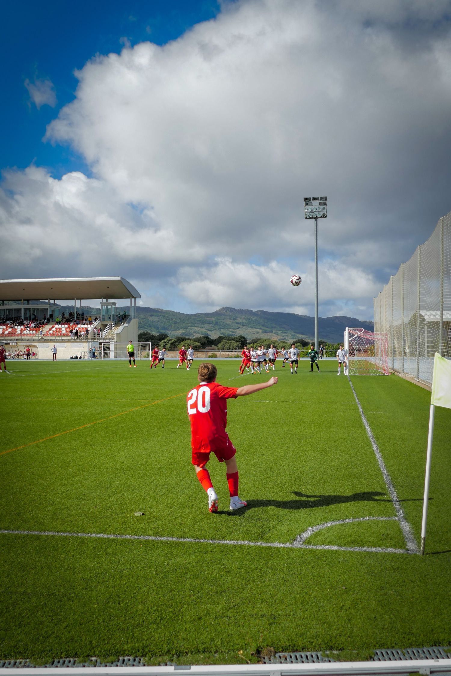 Female soccer player in red number 20 jersey takes a throw-in during a match at a modern stadium.