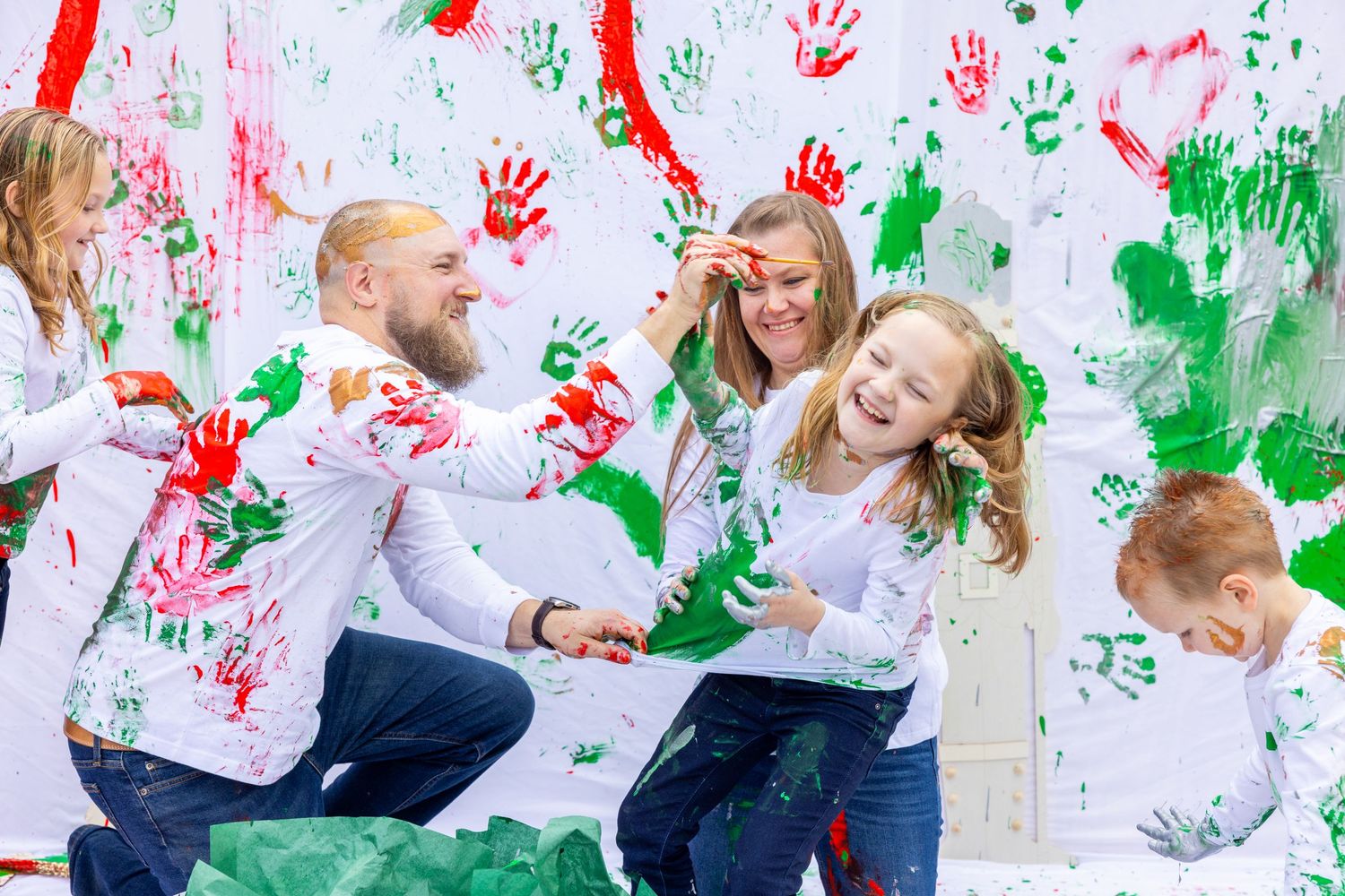 Family having fun with colorful paint handprints on a white wall during a creative photo session. Orlando, Florida