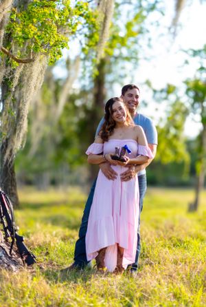 Couple sharing tender moment in pink dress against natural outdoor backdrop. Geneva, Florida