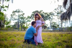 A tender maternity moment captured in a field with Spanish moss draped trees in the background. Geneva, Florida