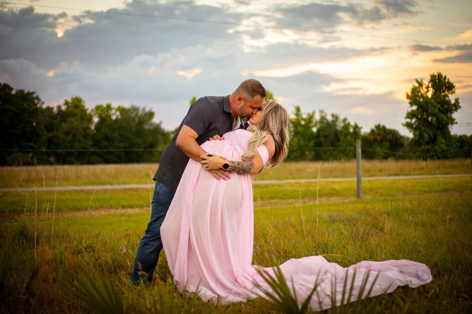 Romantic sunset maternity photo with flowing pink dress in rural field setting. Geneva, Florida