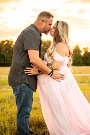 Intimate maternity portrait of couple embracing in pink dress during golden hour. Geneva, Florida