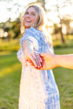 Couple holding hands in sunlit garden with woman in blue floral dress. Geneva, Florida