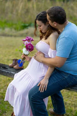 Sweet couple sharing an intimate moment in a lavender dress with purple flowers on a wooden bench. Geneva, Florida