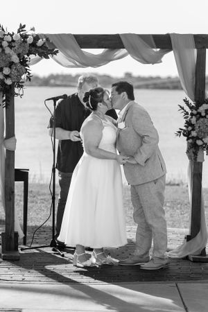 A wedding ceremony under a draped arch with floral arrangements by the water. Merritt Island, Florida