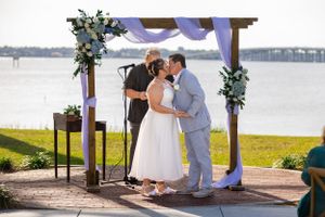 Couple shares romantic moment under floral-decorated wedding arch by waterfront. Merritt Island, Florida
