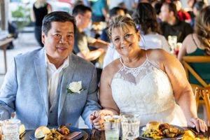 Couple in wedding attire enjoys reception meal at outdoor venue. Merritt Island, Florida