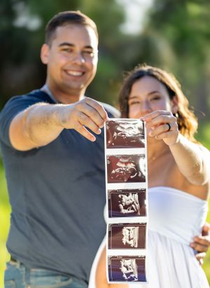Couple holding up ultrasound images outdoors during pregnancy announcement photoshoot. Geneva, Florida