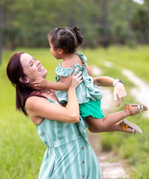 A playful moment captured between two people in matching mint green outfits against a grassy backdrop. Oviedo, Florida