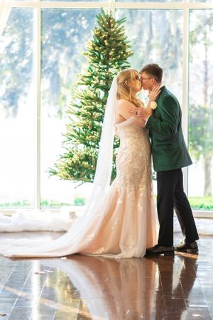 Newlyweds share intimate moment in front of decorated Christmas tree during winter wedding.  Lake Mary, Florida
