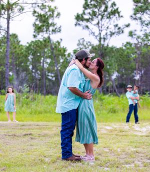 A couple sharing an intimate moment in a field while others look on in the background. Oviedo, Florida
