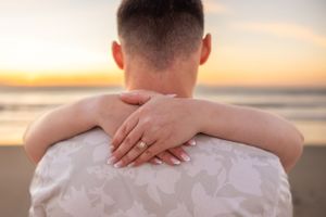 Hands wrapped in embrace against white clothing during golden sunset on the beach. Cape Canaveral, Florida