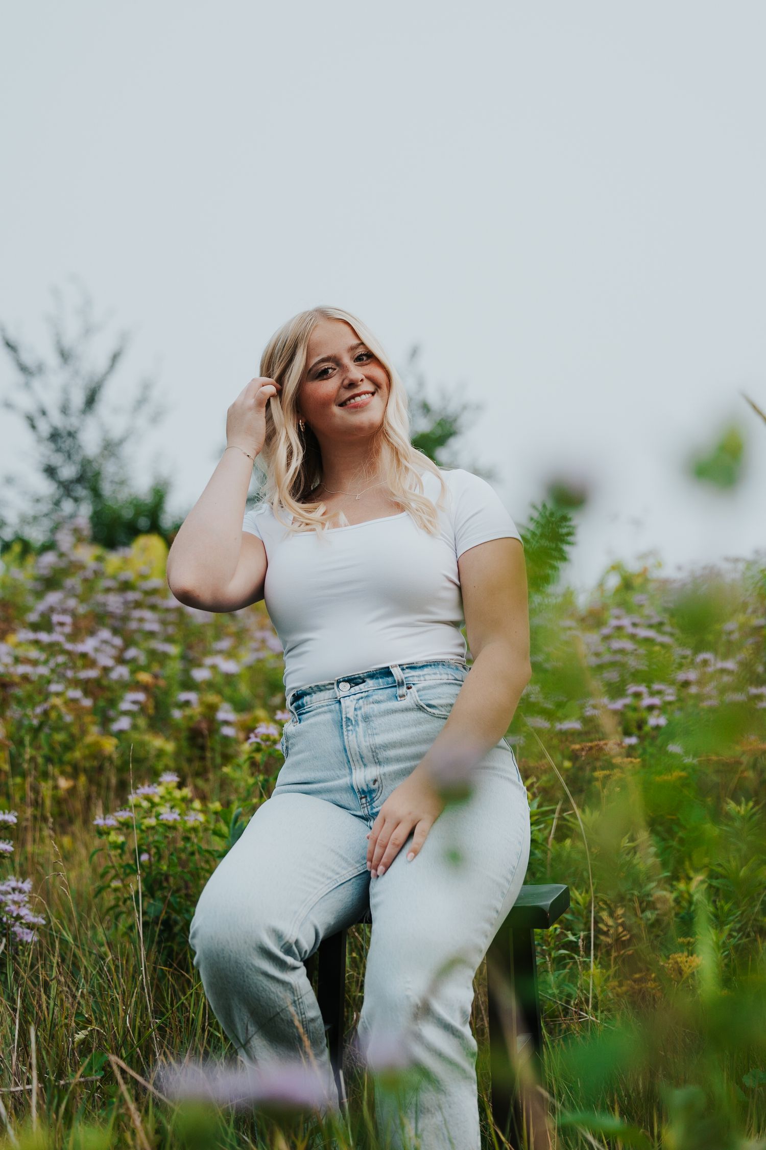 A summer portrait of a woman sitting in a wildflower field.