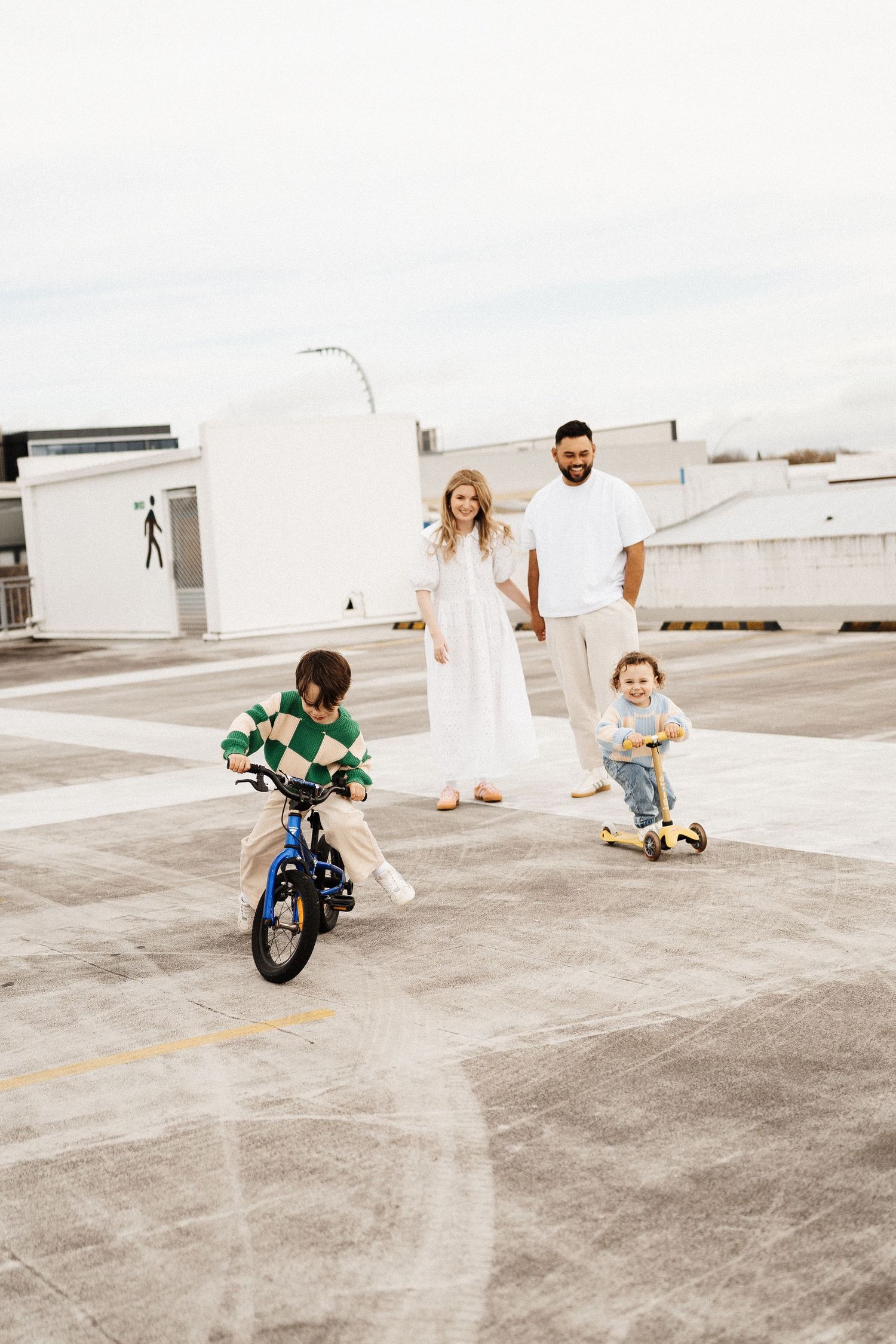 A family enjoying time together on a rooftop with children riding bikes and scooters.
