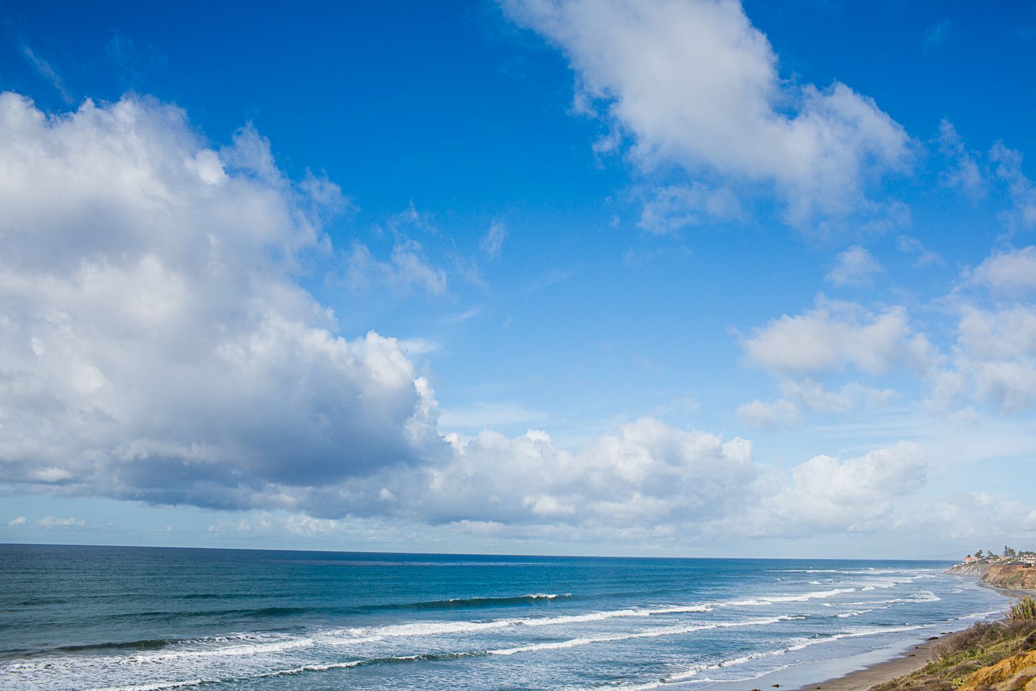 Dramatic cloudy sky over blue ocean waves along California coastline.