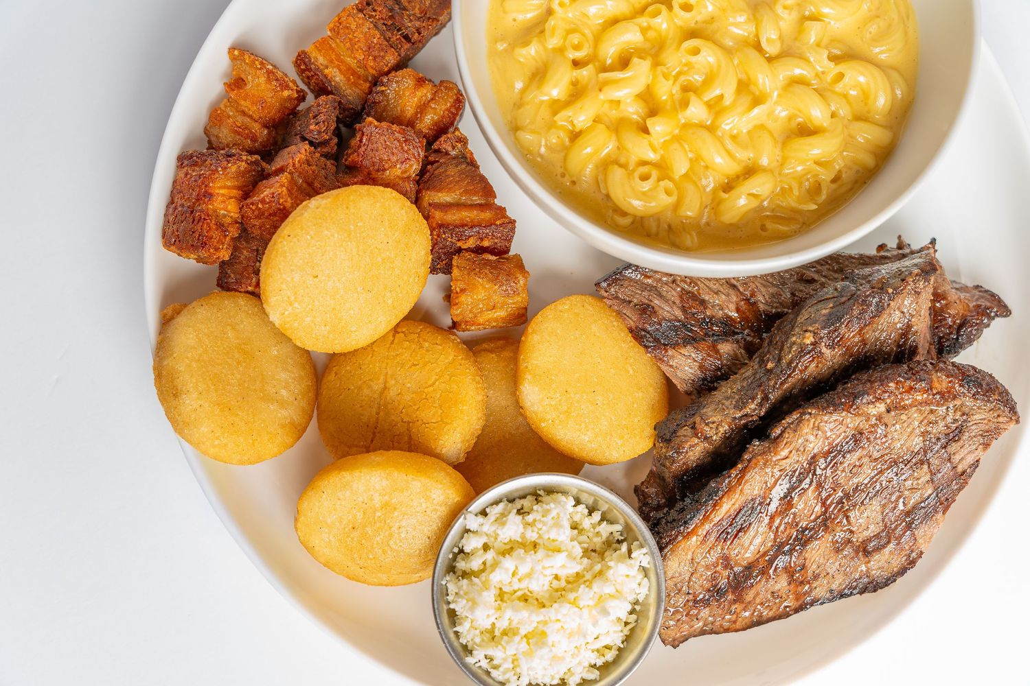 Overhead view of comfort food dishes including mac and cheese, roasted sweet potatoes, and cornbread on a light surface.