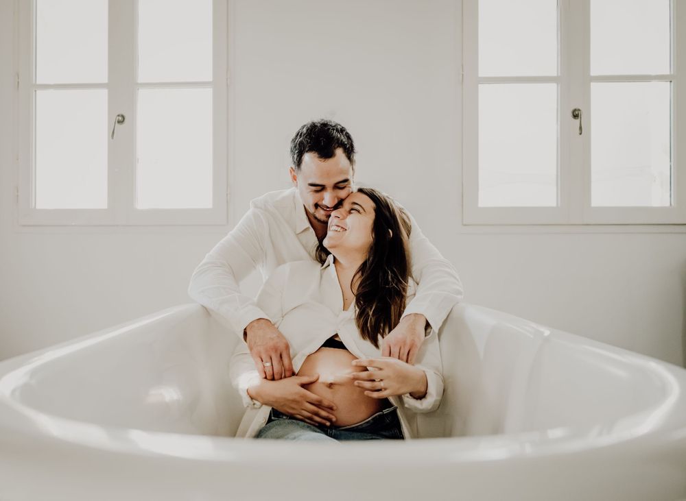 Intimate bathroom photoshoot of a couple embracing in a white bathtub. photographe futur maman Bordeaux, Gironde