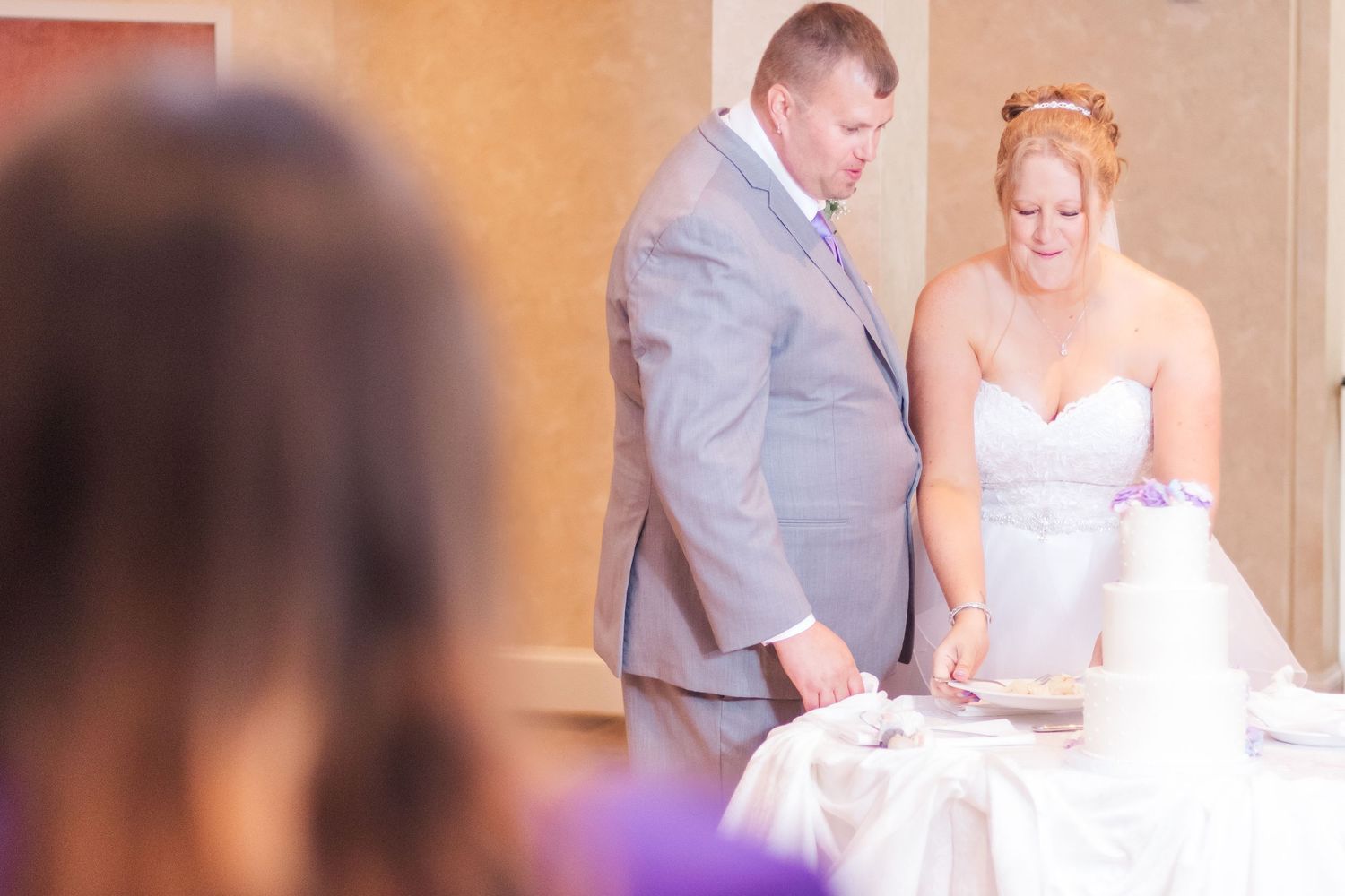 Wedding couple preparing to cut their decorated white cake at reception.