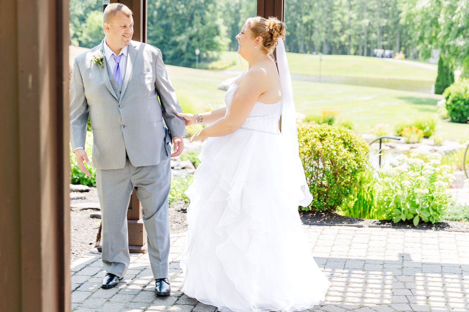 Bride and groom share an intimate moment on a covered walkway overlooking manicured gardens.