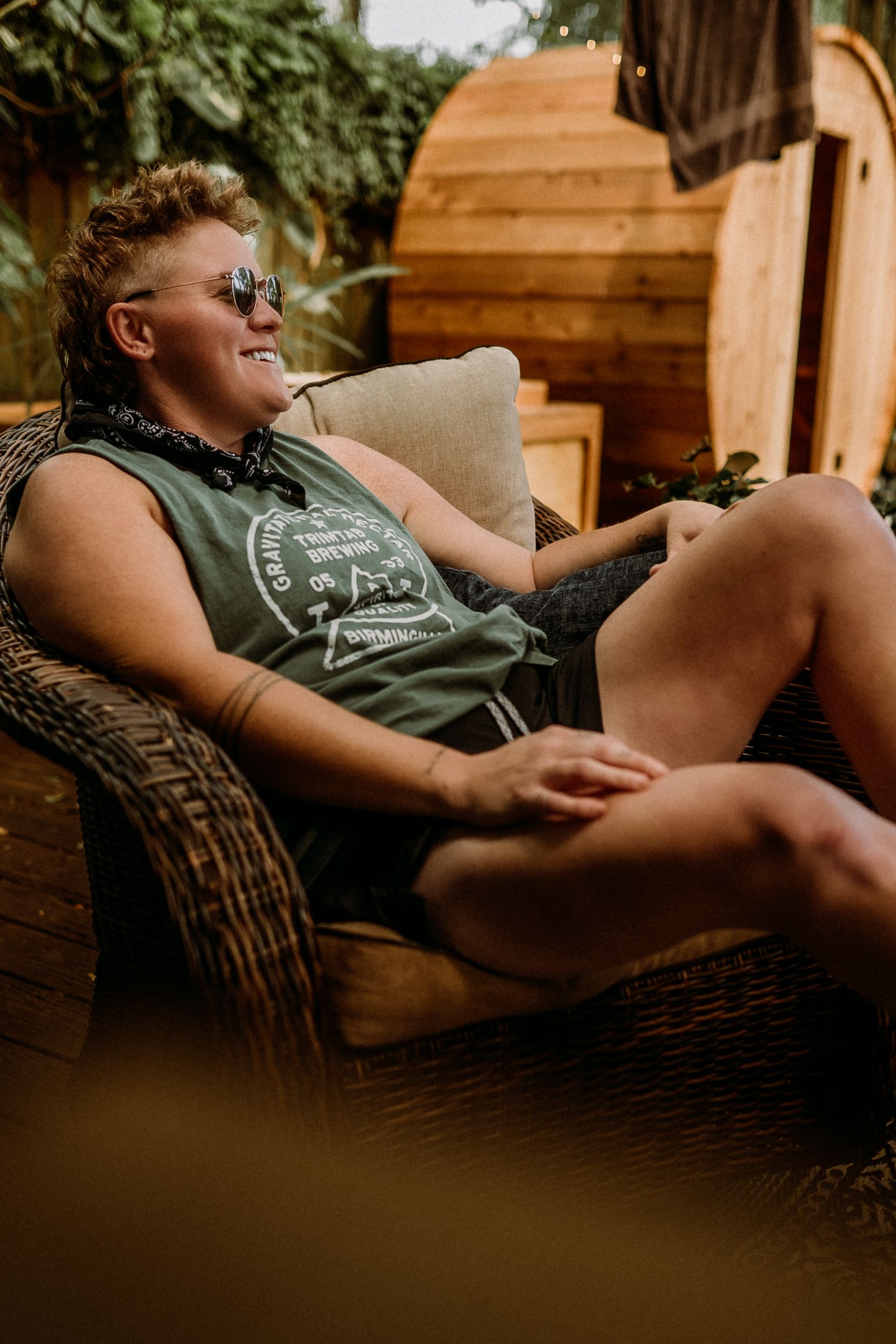 Person relaxing in casual attire on outdoor patio furniture.