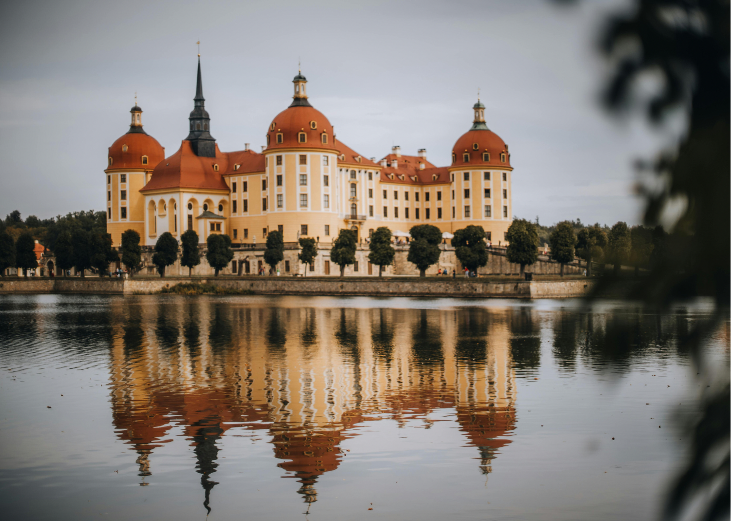 Symmetrical reflection of Moritzburg Castle in still waters during overcast weather. Organized wedding by MyCastleWedding | Dresden.