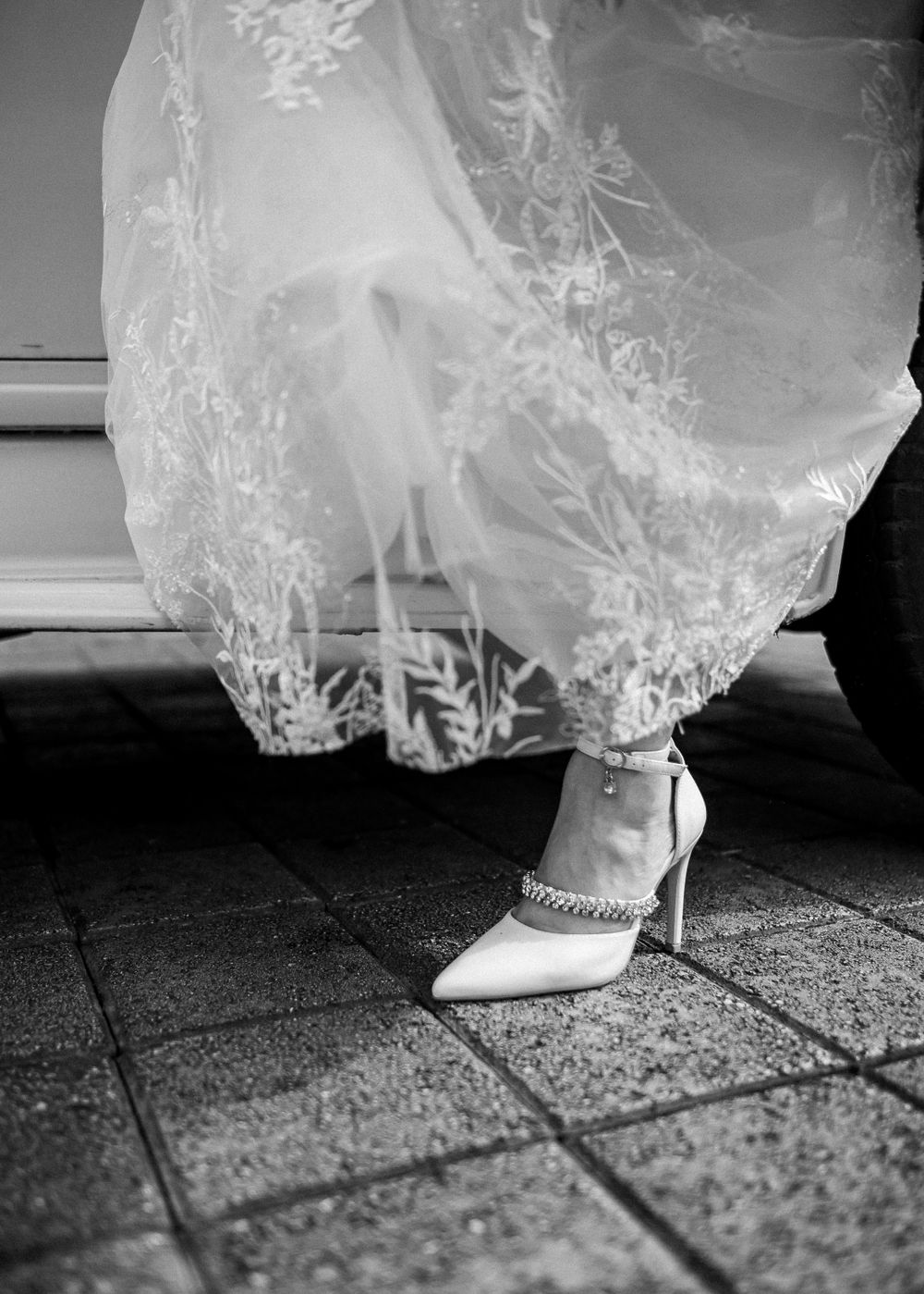 Close-up of bride's elegant white heel and lace wedding dress detail.