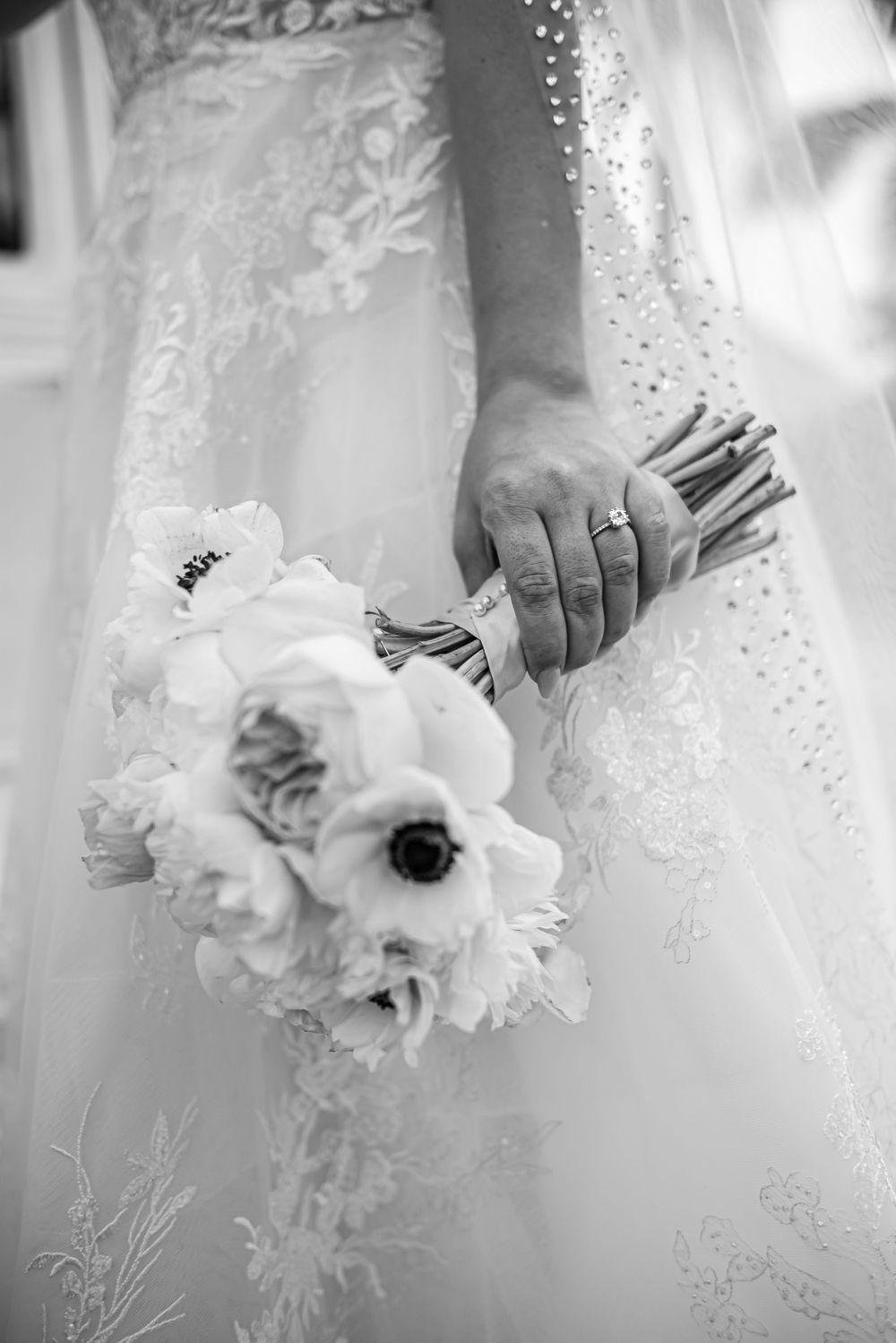 Black and white detail of bride holding delicate white anemone bouquet.