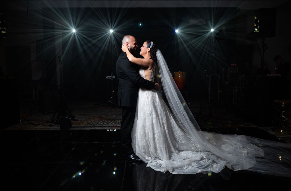 A glamorous wedding photo features dramatic lighting and starburst effects during the couple's dance.