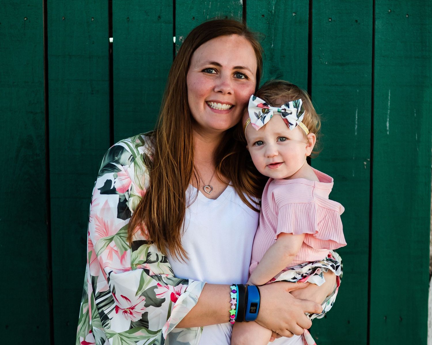 A heartwarming moment against a green wooden backdrop with matching floral outfits.