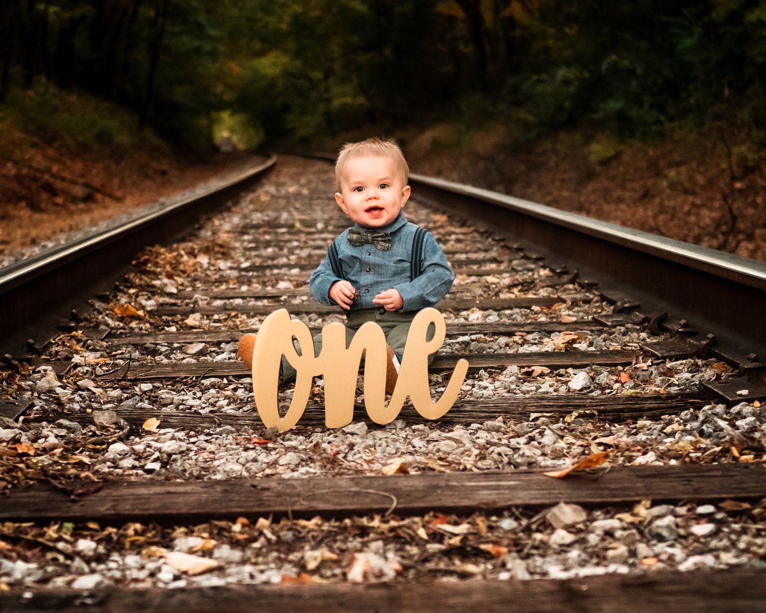 A creative back-to-school photo series taken on rustic railroad tracks with wooden letters and autumn leaves.