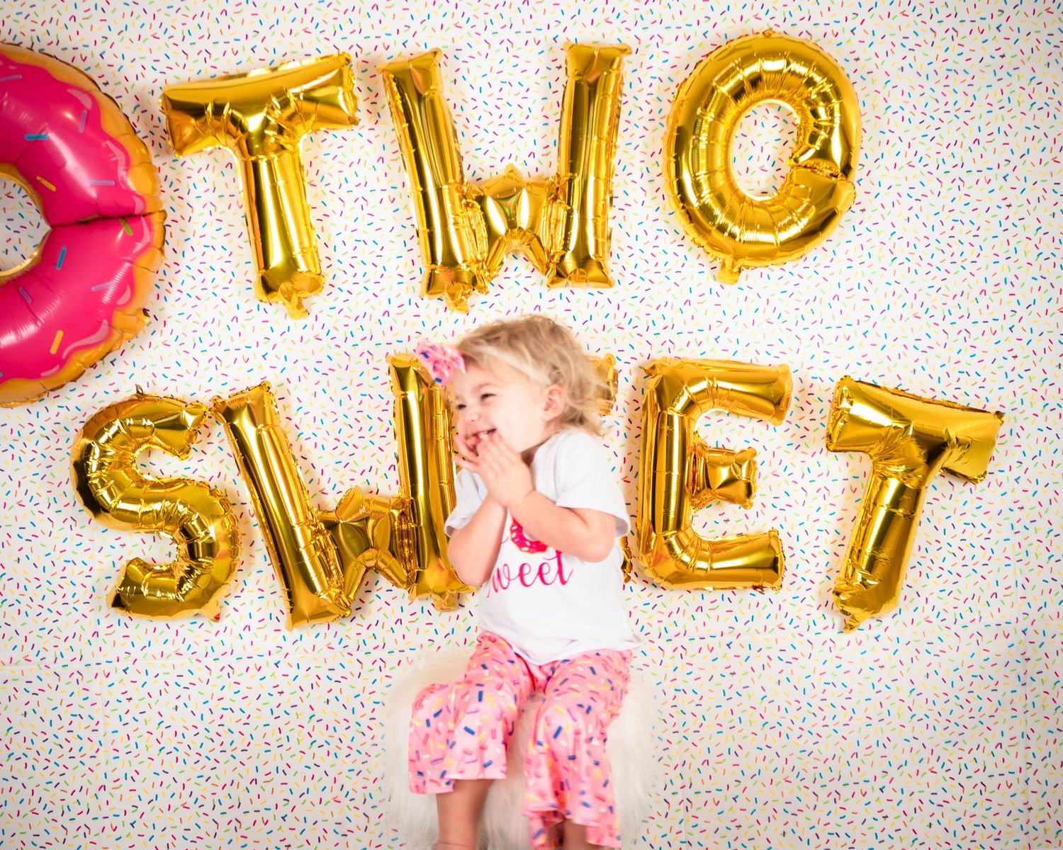 Birthday party decorations featuring gold balloon letters and pink accents.