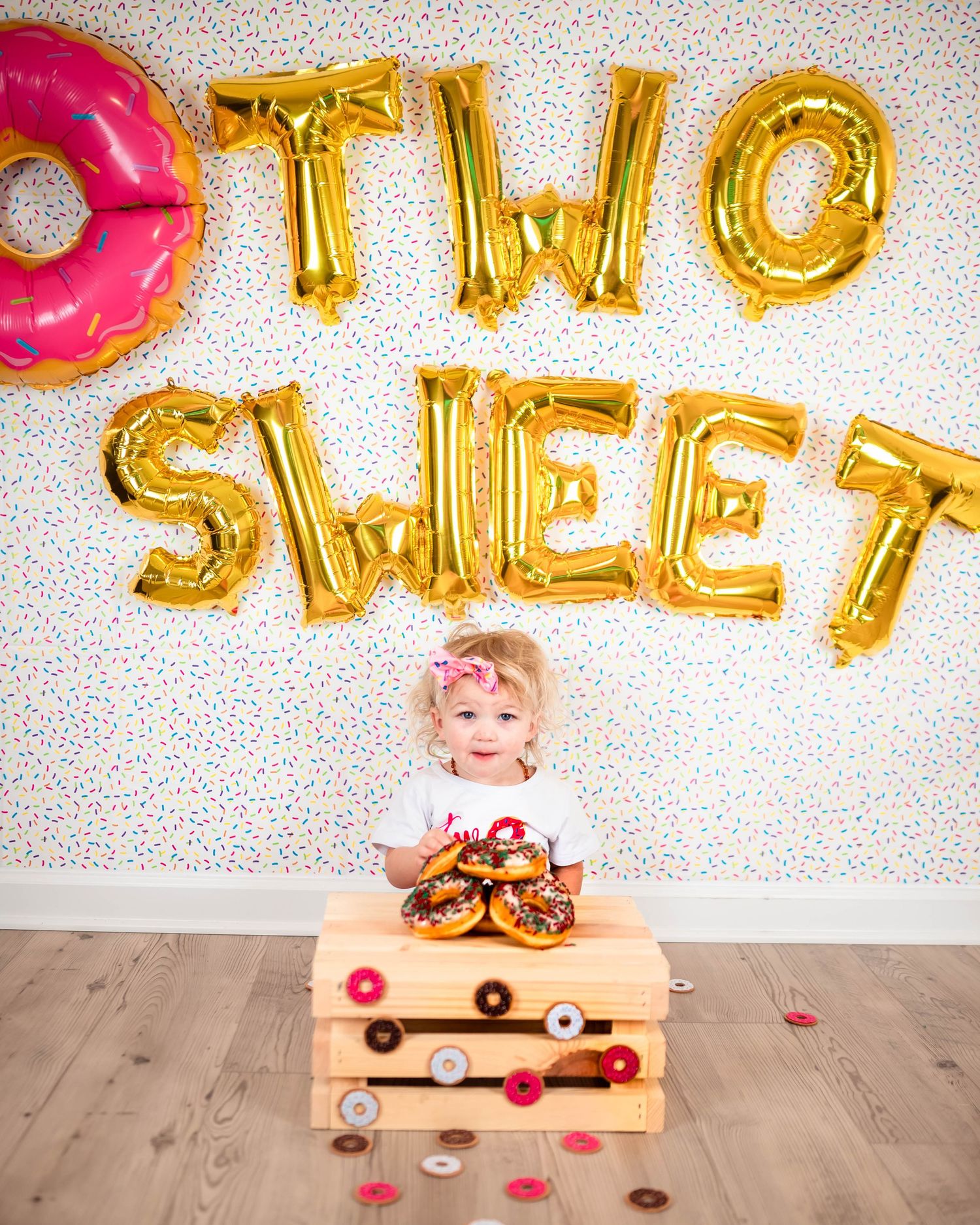 Gold letter balloons spelling 'SWEET' with donuts and pink decorations on a sprinkle background.