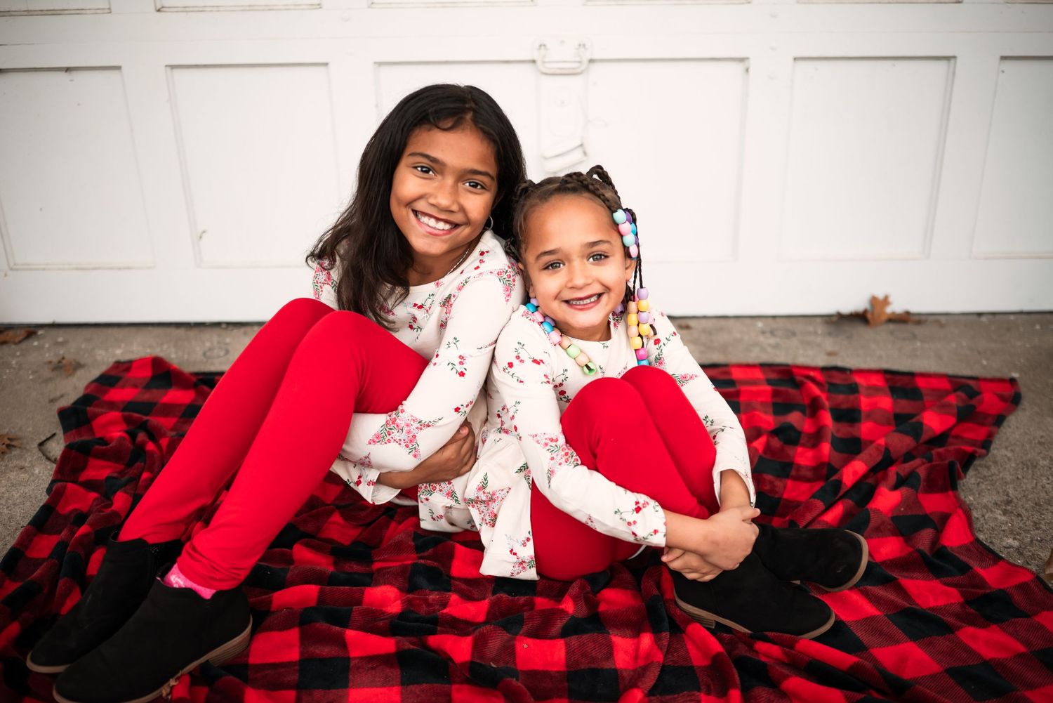 A series of playful family photos showing joyful moments on a red and black buffalo plaid blanket.
