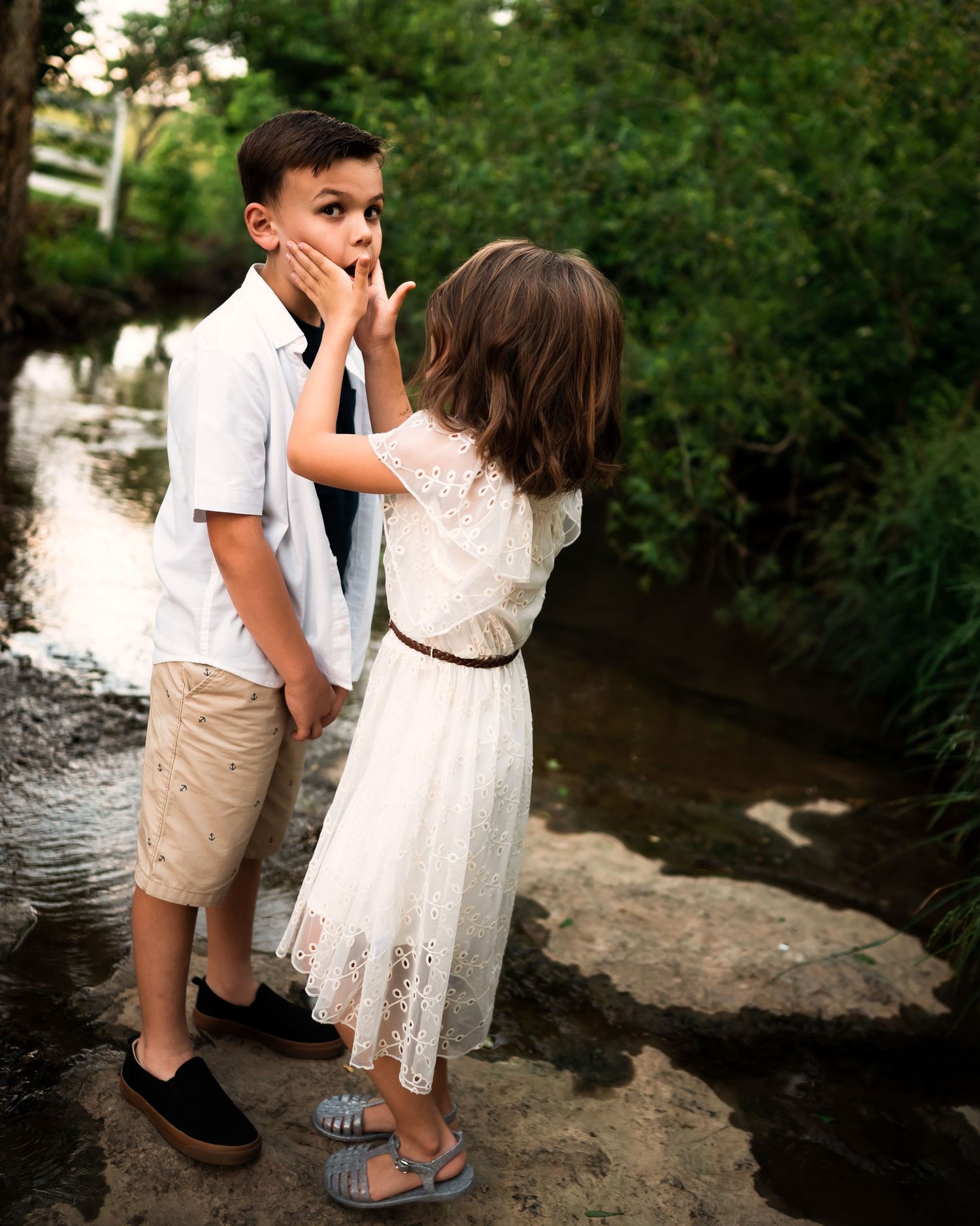 Children playing by a creek in summer attire.