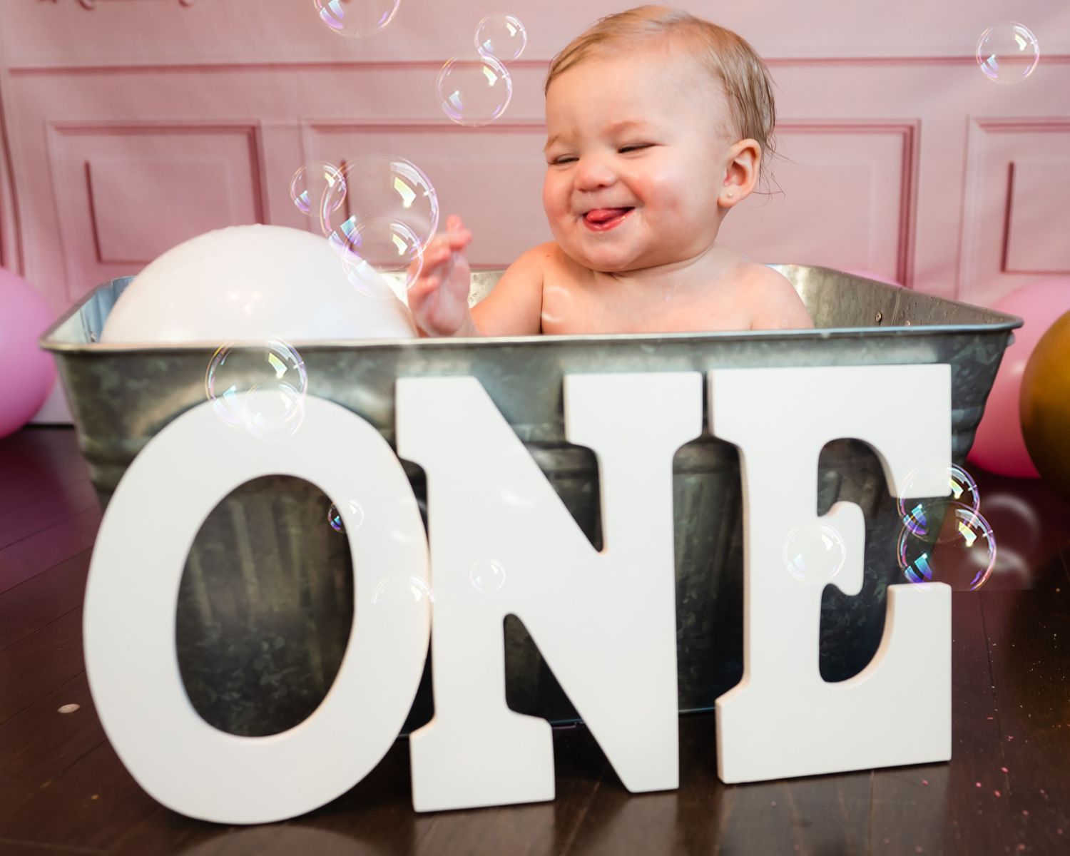 Large white letters spelling 'ONE' displayed with floating bubbles against a pink wall.