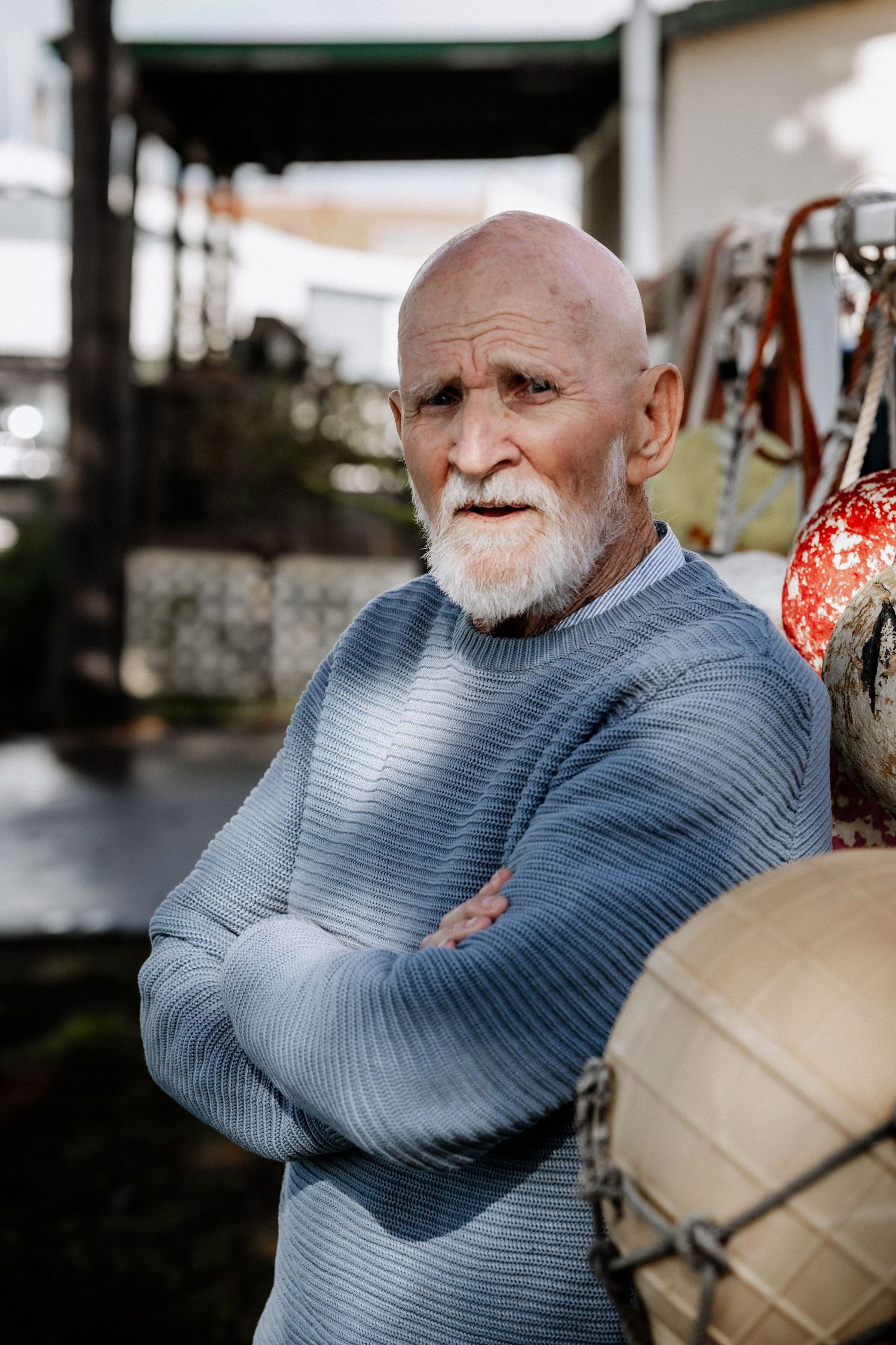 A portrait of an elderly man with his arms crossed, looking directly at the camera.