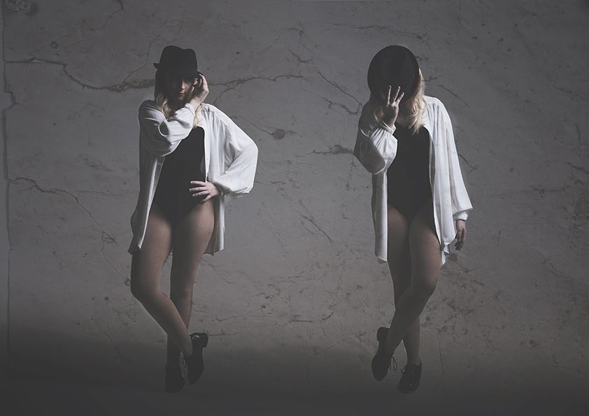 Two figures in black and white posing dramatically against a textured wall.