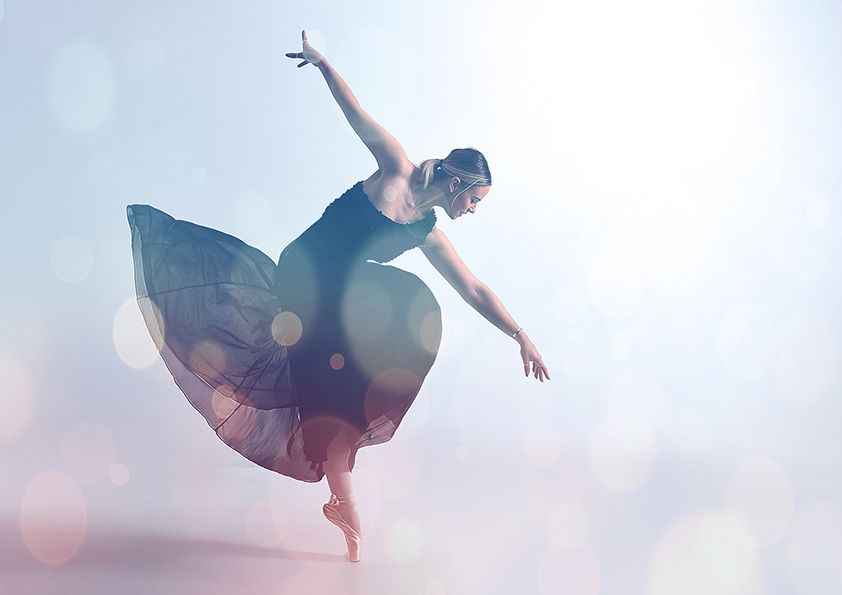Ethereal dance performance with flowing dress and soft bokeh background.