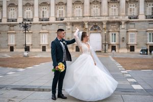 A bride and groom dance joyfully outside the Royal Palace of Madrid with a stunning architectural backdrop.